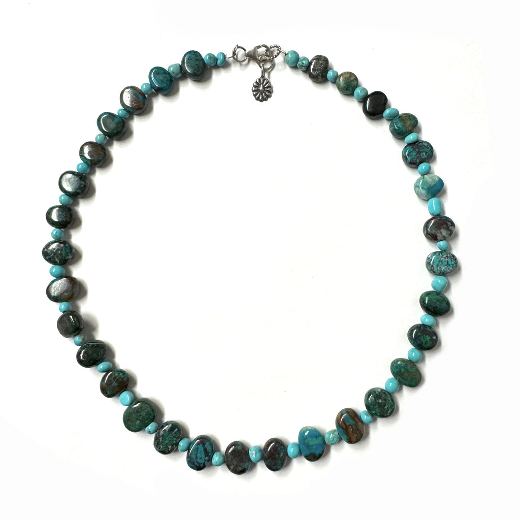 Necklace with turquoise beads in alternating sizes and varying shades on a white background