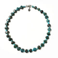Necklace with turquoise beads in alternating sizes and varying shades on a white background