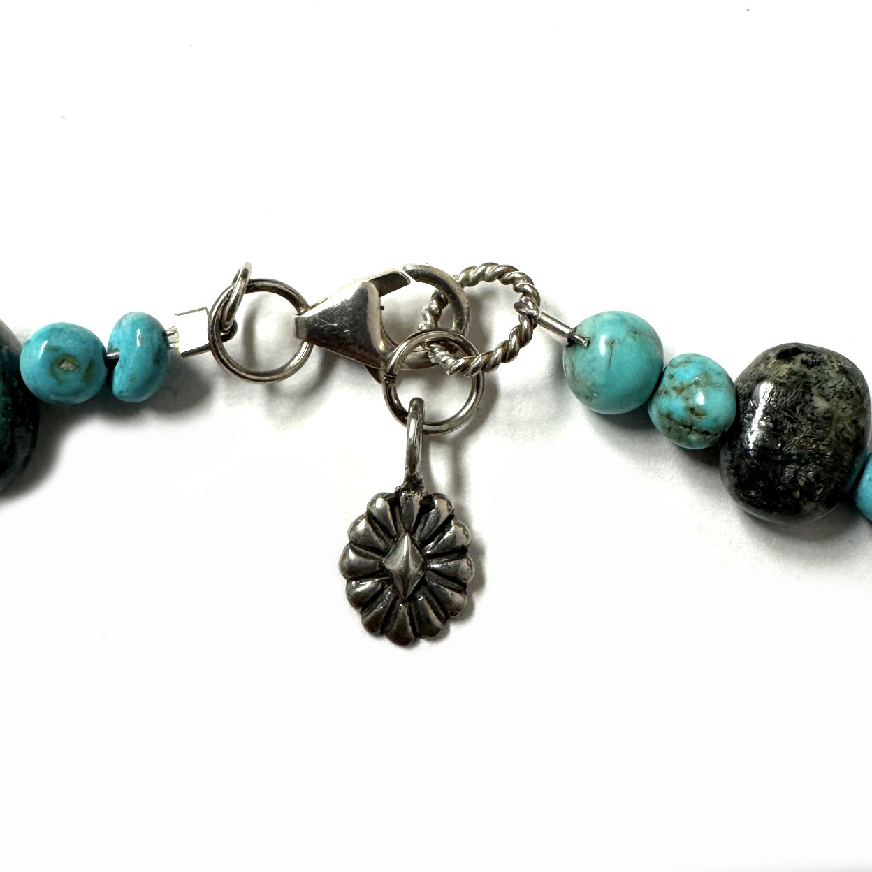 Close-up of a necklace clasp with turquoise beads on a white background