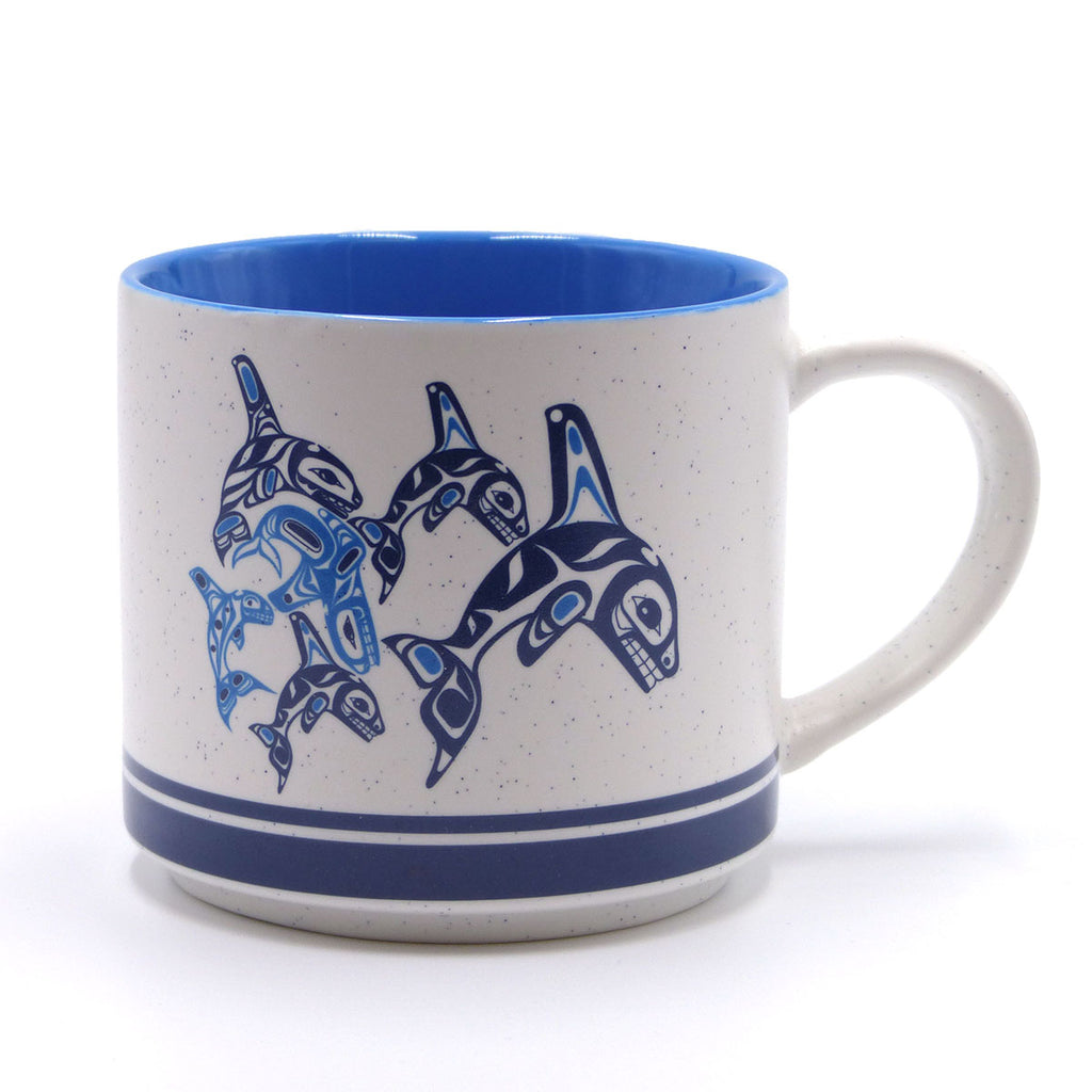 A ceramic mug with blue and white design featuring a graphic of orcas.