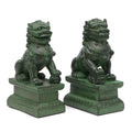 A pair of traditional Chinese Foo lions or Foo dogs, placed on bases, designed to resemble patinated bronze. Front 3/4 view facing right.