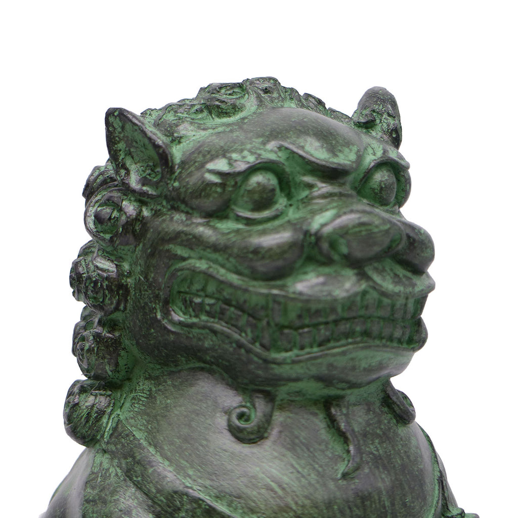 Close up view of the face of a Chinese Foo lion/Foo dog. figure has a finish to resemble patinated bronze.
