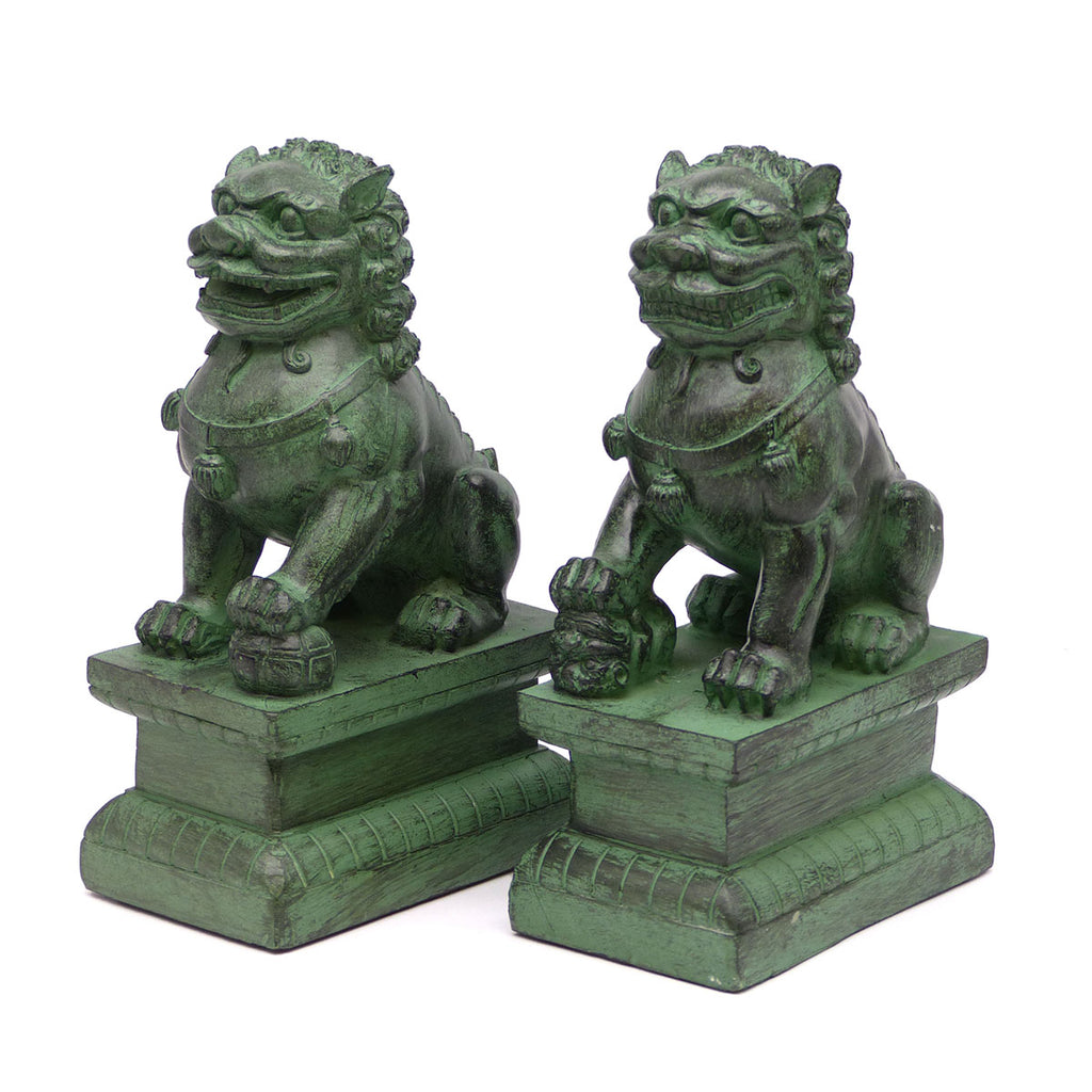 A pair of traditional Chinese Foo lions or Foo dogs, placed on bases, designed to resemble patinated bronze. Front 3/4 view facing left.