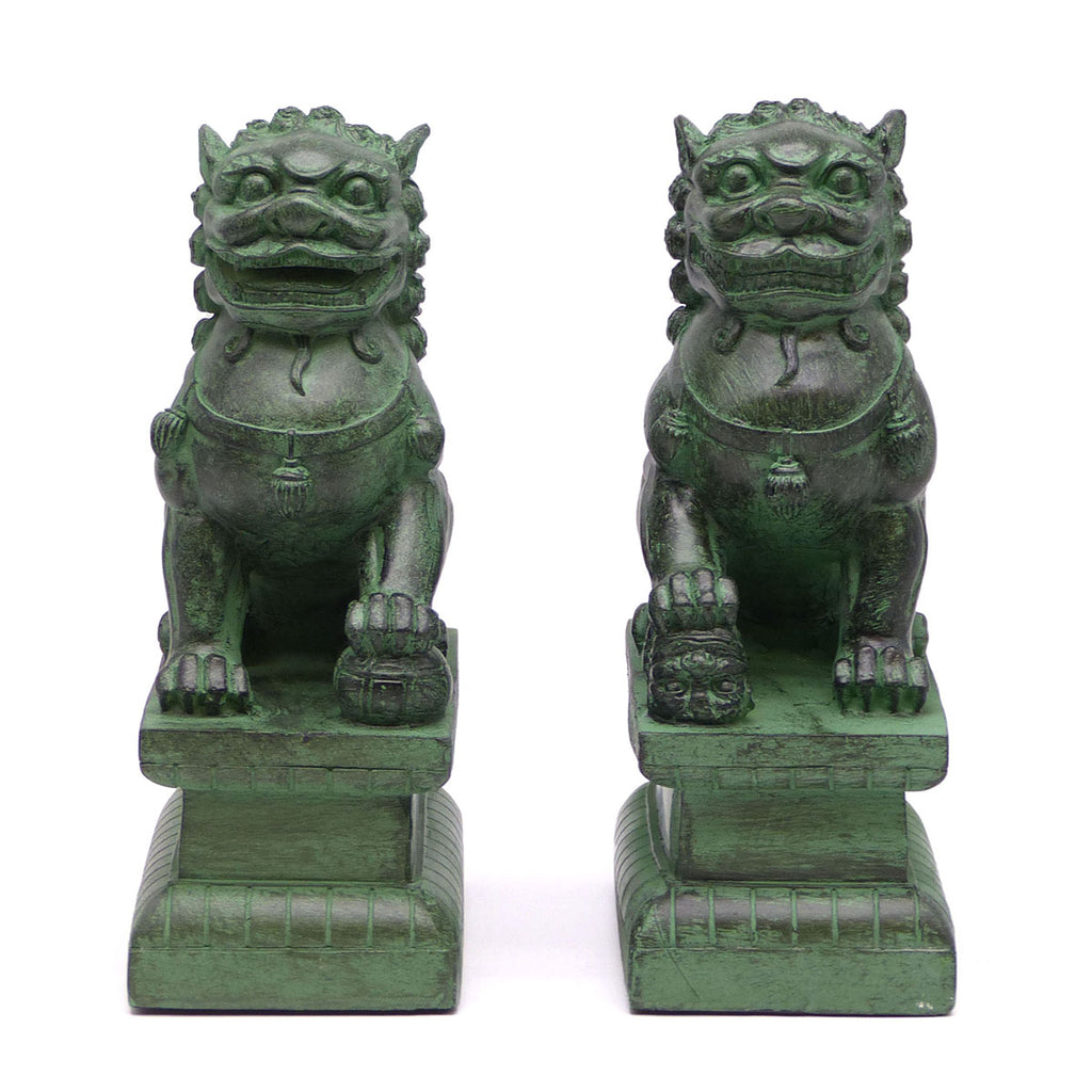 A pair of traditional Chinese Foo lions or Foo dogs, placed on bases, designed to resemble patinated bronze. Front view.